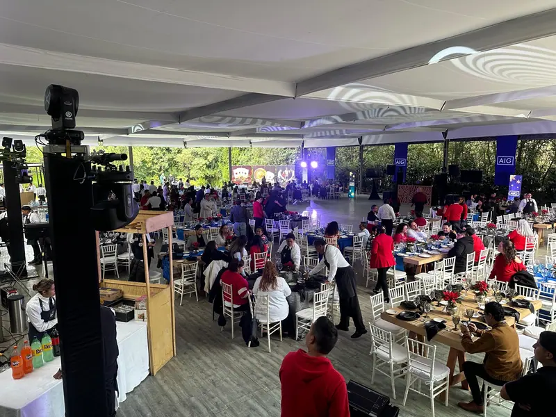 Evento corporativo bajo carpa con mesas, audio y pantallas
