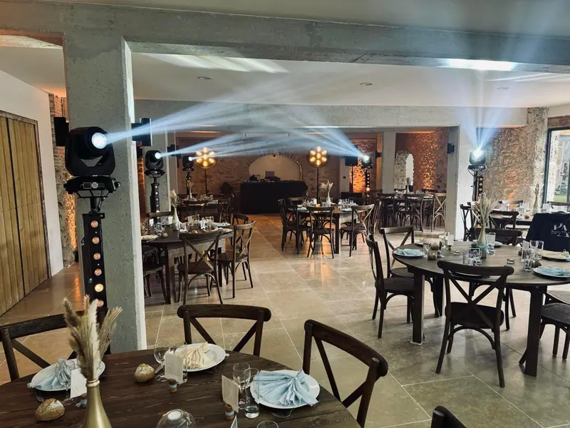 Haces de luz de cabezas móviles sobre un salón con mesas