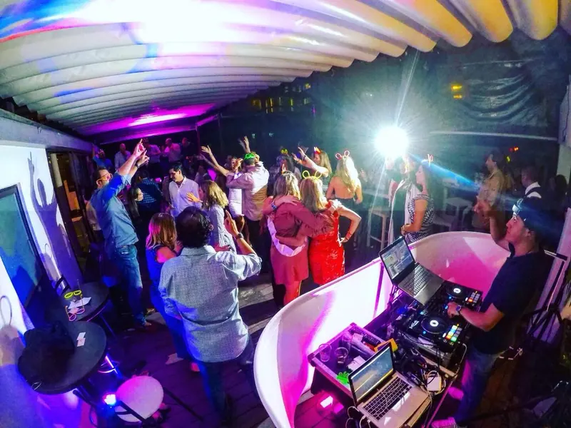 Fiesta temática en terraza con invitados bailando junto a la cabina
